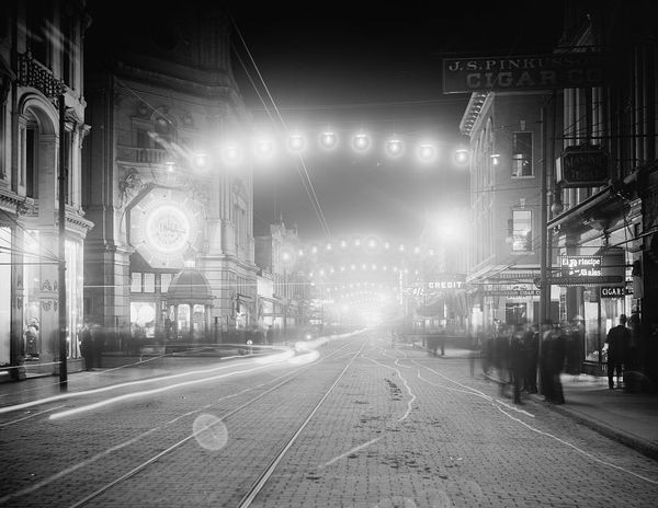 King Street in Charleston at night around 1900, arches of electric lights glowing over the empty street.