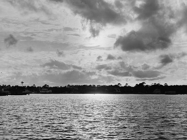 Moonlight breaking through heavy clouds over dark water, about 1910.