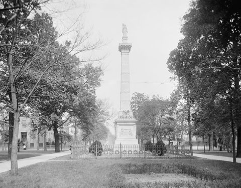 Monterey Square in Savannah around 1900, the Pulaski Monument framed by tall trees.